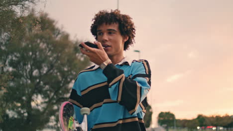 Millennial-skater-speaking-cellphone-sunset-city-closeup.-Zoomer-recording-phone