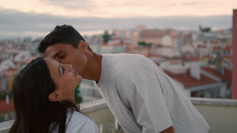 Gentle-spouse-kissing-wife-sunset-balcony-closeup.-Couple-having-romantic-dinner
