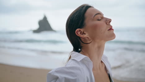 Woman-enjoy-breeze-standing-near-waves-close-up.-Model-posing-seashore-vertical