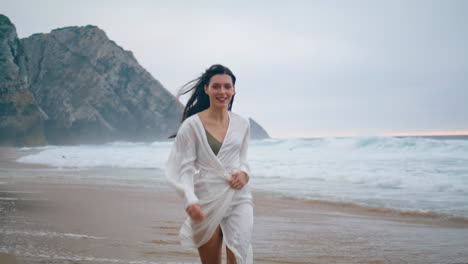 Serene-girl-running-ocean-beach-on-cloudy-day.-Woman-jogging-waves-vertically