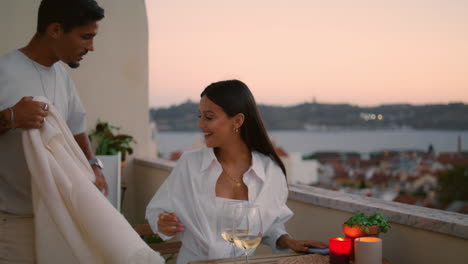 Gentle-man-bringing-blanket-to-wife-at-sunset-balcony.-Romantic-couple-terrace