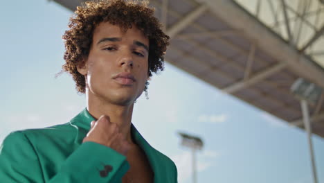 Curly-student-looking-camera-at-stadium-fashion-portrait.-Serious-model-posing