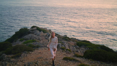 Lovely-model-climbing-sea-cliff-alone.-Blonde-woman-walking-hill-water-horizon