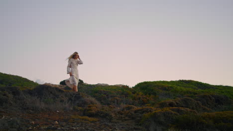 Stylish-woman-exploring-landscape-alone-vertical.-Blonde-girl-walking-at-sunset