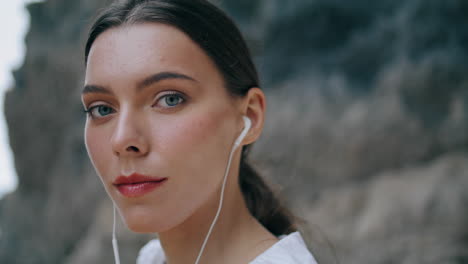 Portrait-woman-listening-music-by-earphones-sandy-hill.-Girl-enjoy-song-vertical