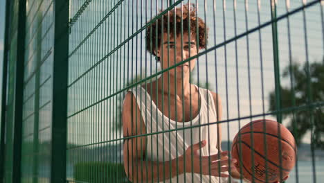 Junger-Sportler-Posiert-Auf-Dem-Basketballplatz-Im-Porträt.-Lockiger-Bösewicht-Schaut-In-Die-Kamera