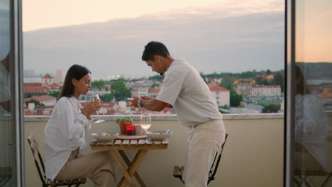 Marido-Cariñoso-Sirviendo-Mesa-Balcón-Del-Hotel-Primer-Plano.-Cena-Romantica-Pareja-Joven