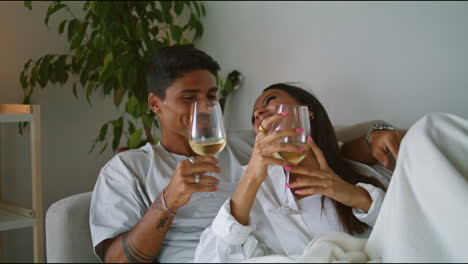 Young-spouses-laughing-hotel-evening-closeup.-Relaxed-couple-drinking-wine-home