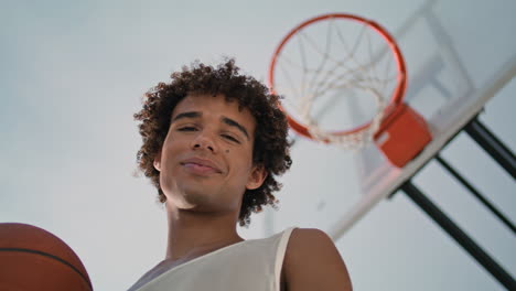 Smiling-sportsman-holding-ball-at-stadium.-Basketball-player-posing-at-street