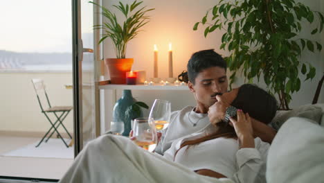 Romantic-family-kissing-flat-interior-closeup.-Couple-resting-together-with-wine