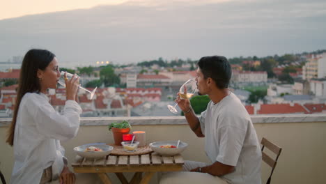 Positive-couple-celebrating-date-sunset-terrace-closeup.-Family-clinking-glasses