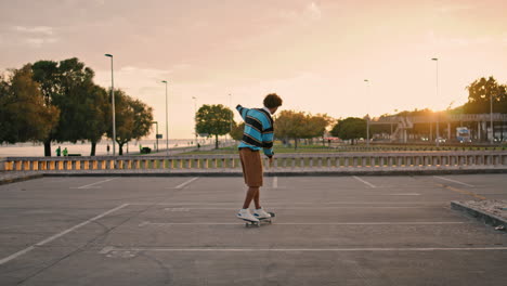 Young-man-balancing-skateboard-at-evening-back-view.-Guy-riding-skate-vertically