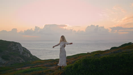 Dress-model-turning-sunset-valley.-Cute-woman-spinning-enjoying-ocean-cliff