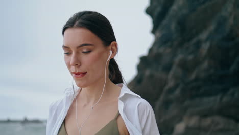 Woman-walking-shore-headphones-close-up.-Girl-listening-songs-vertical-oriented