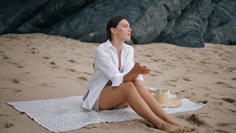 Woman-sitting-blanket-beach-looking-seascape.-Girl-relaxing-at-coverlet-vertical