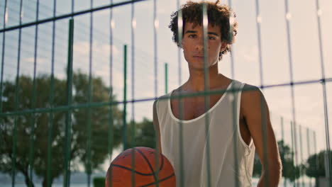 Modern-sportsman-playing-basketball-on-sports-field-portrait.-Guy-looking-camera