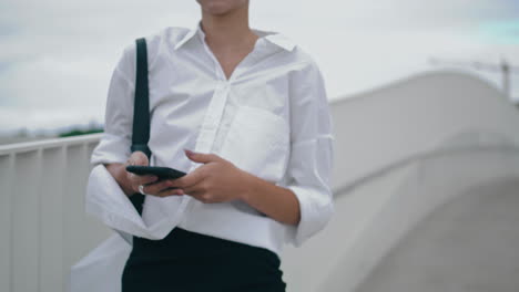 Unknown-business-woman-messaging-on-smartphone-walking-city-street-close-up.