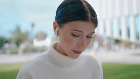 Portrait-woman-talking-outdoors-using-wireless-earbuds.-Girl-using-headphones.