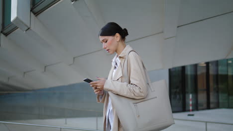 Businesswoman-messaging-smartphone-outside.-Worried-woman-standing-vertically