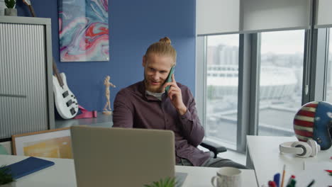 Laughing-guy-chatting-cellphone-in-office-close-up.-Startuper-having-phone-call