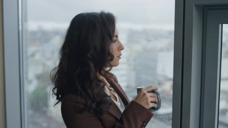 Office-manager-drinking-coffee-standing-at-window-close-up.-Woman-work-break.