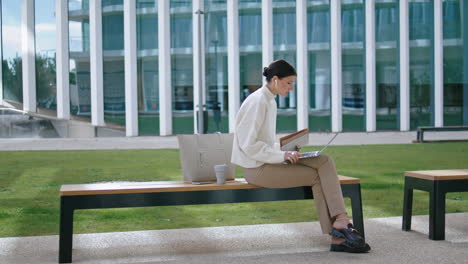 Woman-talking-video-chat-laptop-sitting-bench-outdoors.-Girl-conducting-webinar.