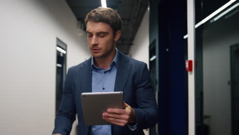 Smiling-executive-using-tablet-computer.-Handsome-man-walking-business-center