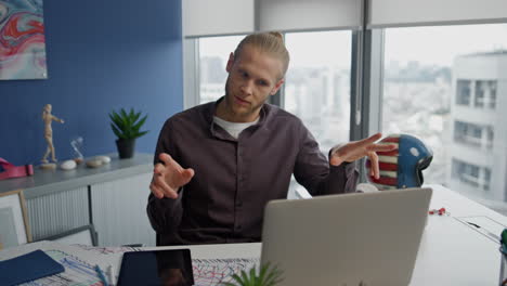 Gesturing-man-calling-laptop-at-office-close-up.-Serious-designer-video-chatting