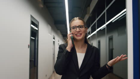 Happy-executive-talking-mobile-phone.-Successful-businesswoman-walking-hallway