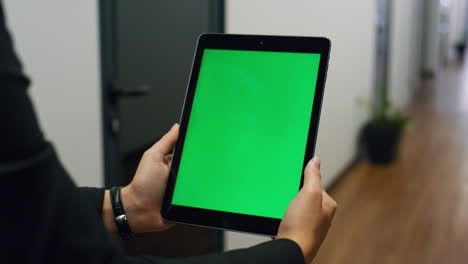 Hands-holding-green-tablet-template-in-office-closeup.-Employee-video-calling