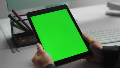 Hands-hold-green-tablet-at-contemporary-workplace-closeup.-Freelancer-use-chroma