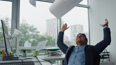 Smiling-businessman-throwing-papers-at-glass-workplace.-Happy-manager-celebrate