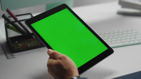 Closeup-green-screen-tablet-in-hands.-Office-manager-holding-mockup-device