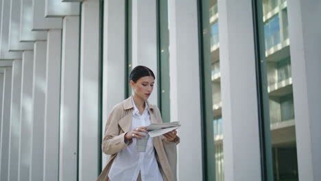 Businesswoman-walking-reading-newspaper-on-street.-Girl-holding-press-vertically