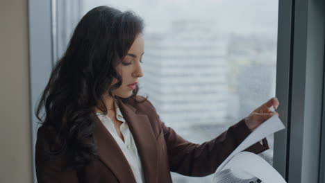 Woman-ceo-reading-documents-business-contract-standing-at-office-window-close-up