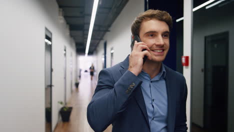 Trabajador-Emocionado-Habla-Con-Teléfono-Inteligente-En-La-Oficina.-Empresario-Sonriente-Comparte-Buenas-Noticias