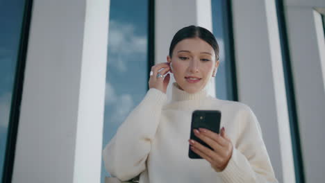 Woman-making-video-call-by-smartphone-wearing-wireless-headset-close-up-vertical