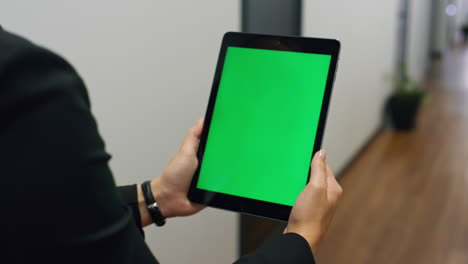 Closeup-chroma-key-tablet-in-manager-hands.-Unknown-woman-walking-hallway-talk