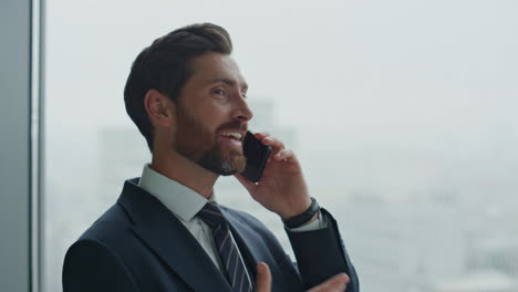 Entrepreneur-speaking-mobile-phone-near-office-window-close-up.-Business-talk.