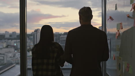 Young-coworkers-silhouettes-talking-dusk-office-closeup.-Unknown-couple-speaking