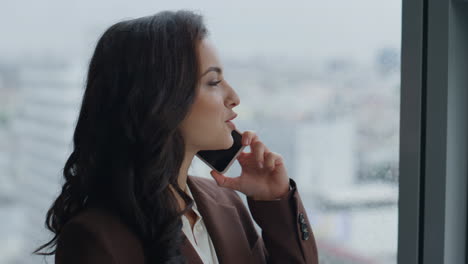 Director-have-business-call-standing-at-office-window-close-up.-Lady-ceo-talking