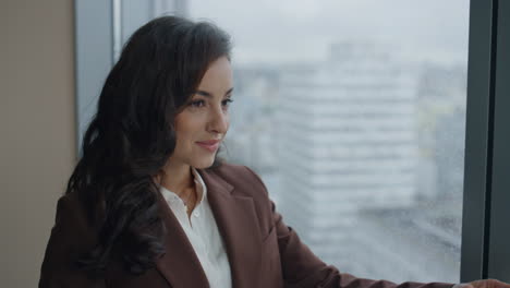 Executive-manager-satisfied-documents-standing-at-office-window-smiling-close-up
