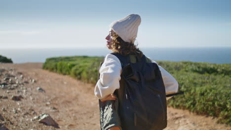 Tourist-walking-rocky-pathway-at-ocean-shore.-Relaxed-girl-going-with-backpack