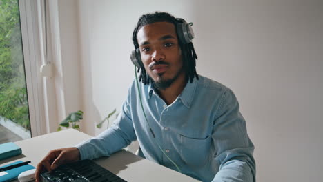 Dreadlocks-man-using-console-at-table-portrait.-Sound-producer-smiling-camera