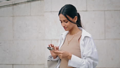 Happy-girl-messaging-smartphone-street-vertical-closeup.-Smiling-lady-texting