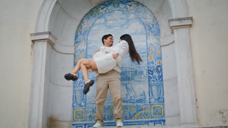 Enamoured-sweethearts-embracing-ceramic-tile-place.-Man-carrying-woman-at-hands