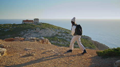 Hiking-girl-talking-phone-at-calm-ocean-sunset-vertical.-Tourist-walk-mountain