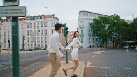 Excited-pair-running-urban-street.-Laughing-man-woman-having-fun-crossing-road