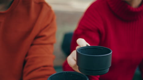 Hands-holding-thermos-cup-on-nature-close-up.-Man-pouring-beverage-on-picnic.