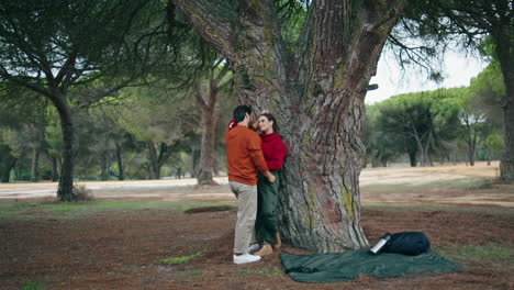 Pareja-De-Pie-Apoyado-En-Un-árbol-Abrazándose.-Linda-Pareja-Hablando-Abrazándose-En-El-Parque-Natural.